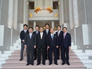 議場正面で記念撮影、後ろのモチーフは馬